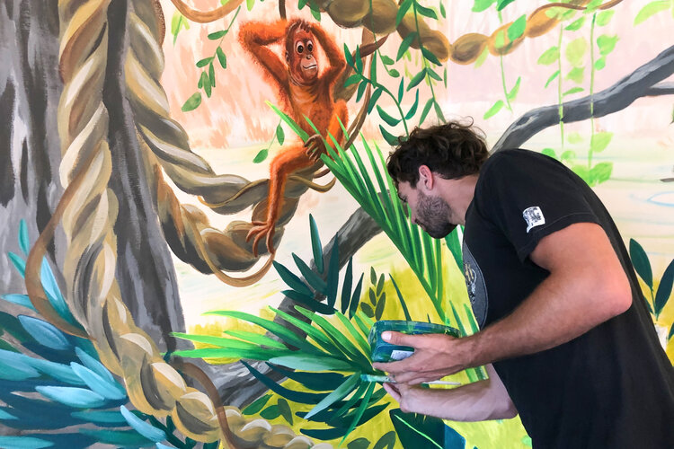 Ein Dschungelbild wird auf die Wand gezeichnet.