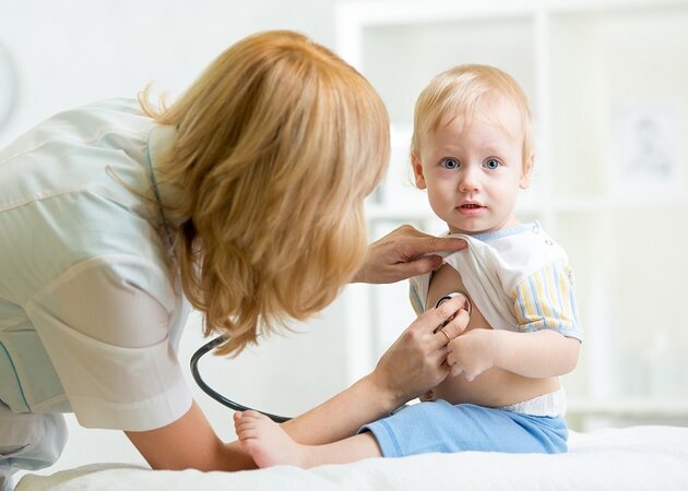 Ärztin untersucht Kind mit einem Stethoskop.