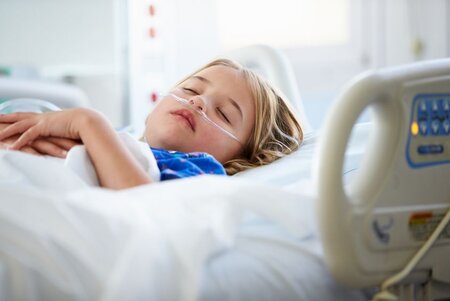 Kind schläft im Krankenbett