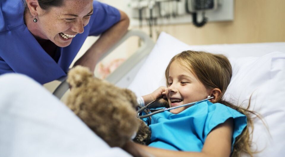 Beispielbild für eine Kinderklinik, Pflegerin und Mädchen lachen